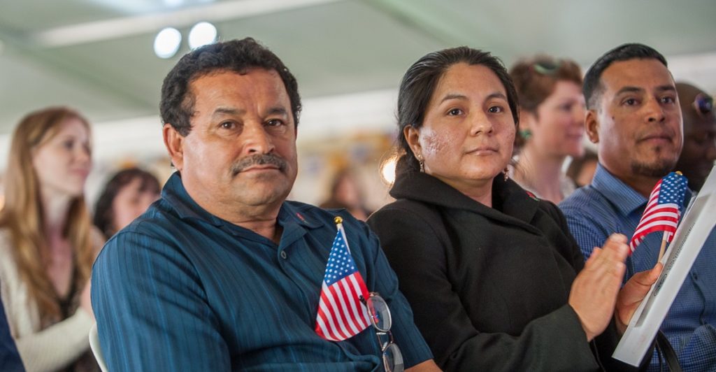 New U.S. citizens watch speaker at a naturalization ceremony