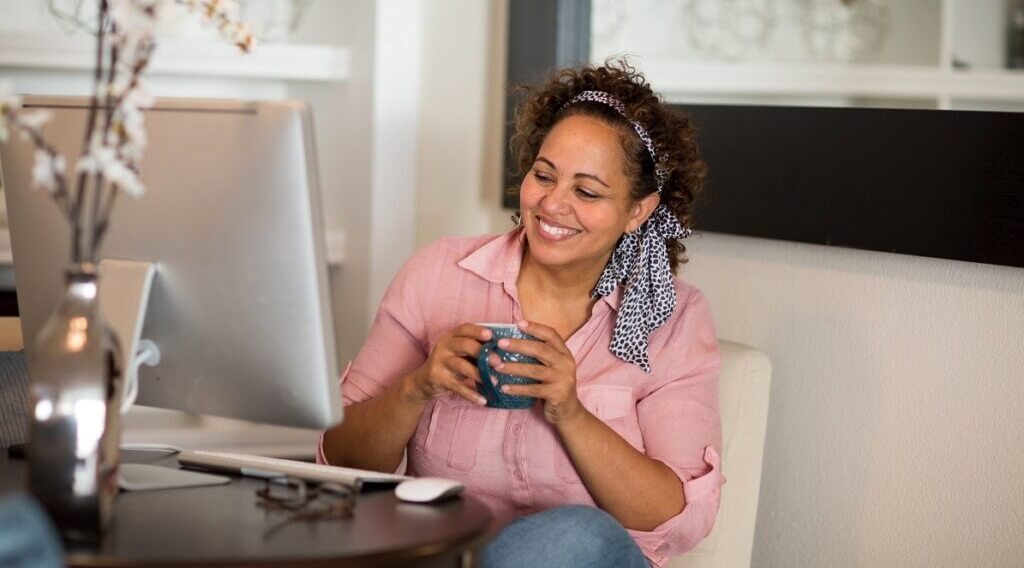 An immigrant visa applicant drinks coffee while preparing DS-260 on the website