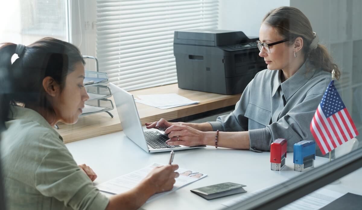 Woman at consular interview for an immigrant visa signs form