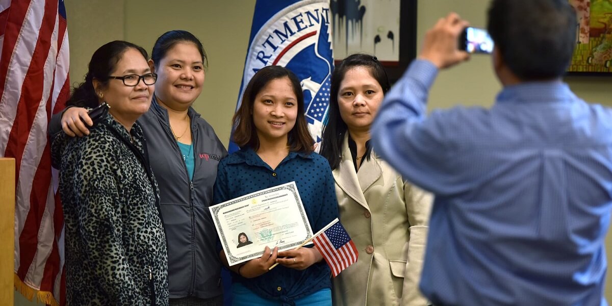 Woman poses with her Certificate of Naturalization and family members